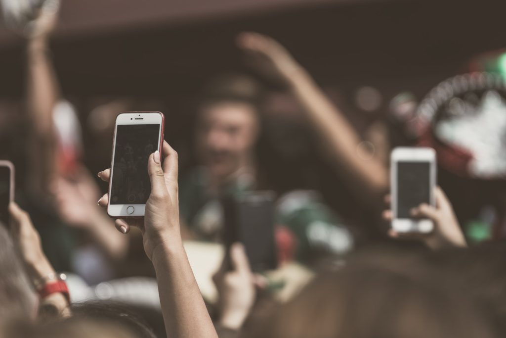 SMS corporativo: diversas pessoas com as mãos estendidas portando smartphones.