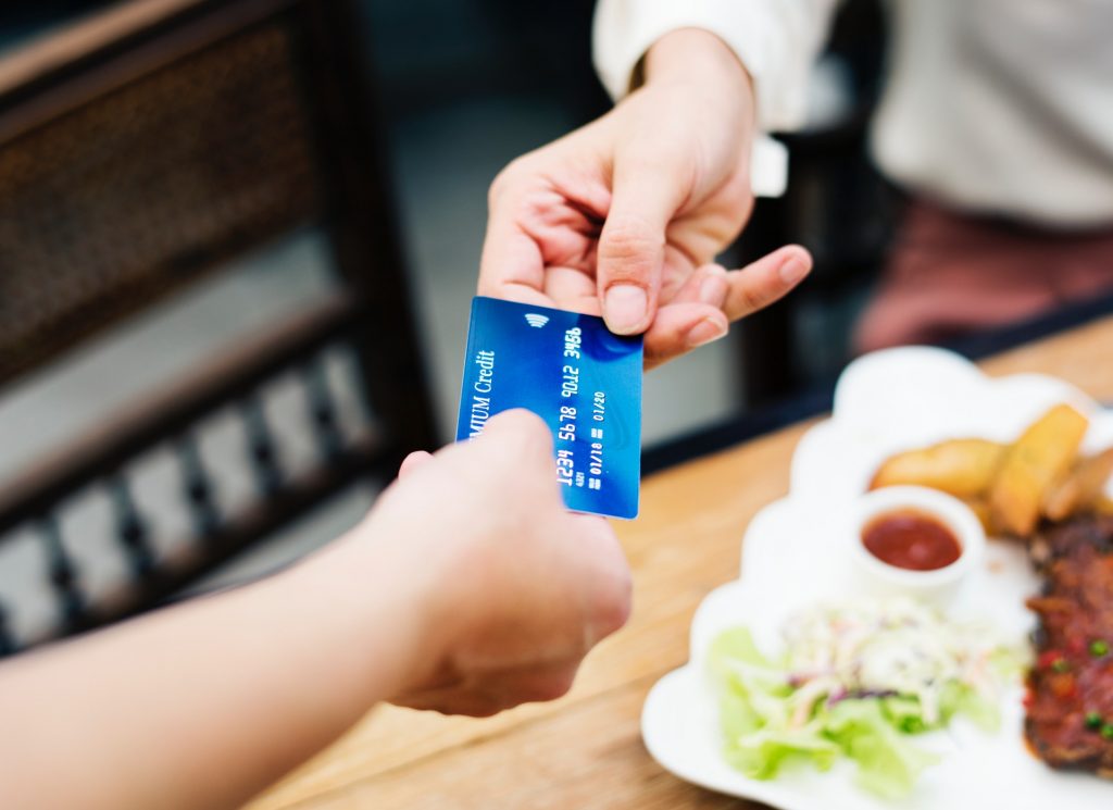 Fidelização do cliente: imagem de uma mão segurando o cartão de crédito e realizando uma compra.