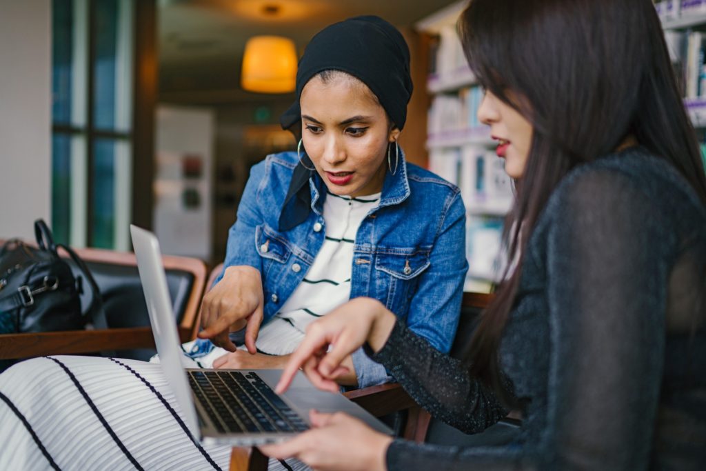 Gestão em nuvem: duas mulheres conversando e apontando para o computador.