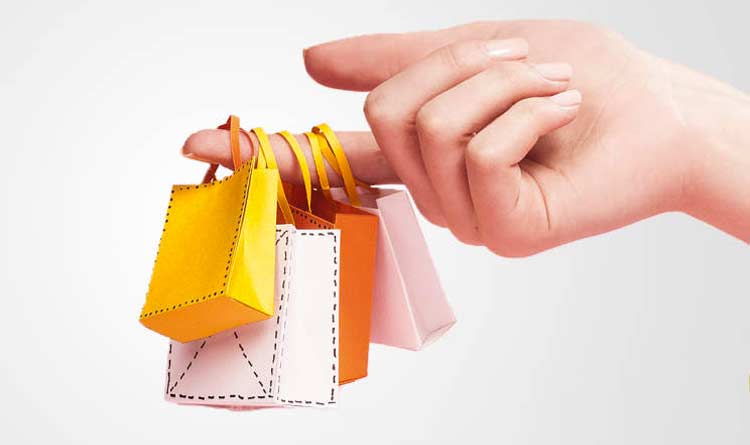 Comportamento do consumidor: mão segurando pequenos carrinhos de compra.