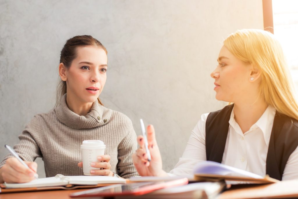 Duas mulheres conversando em um ambiente empresarial.