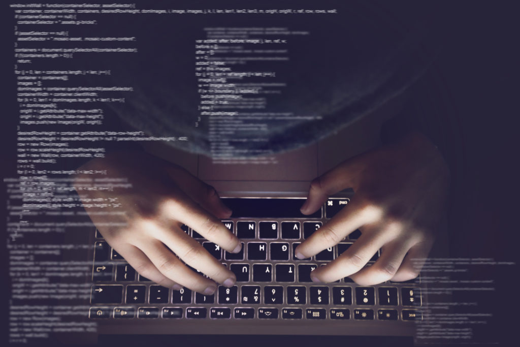 Phishing: homem digitando em um teclado, com códigos de computador aparecendo fora da tela
