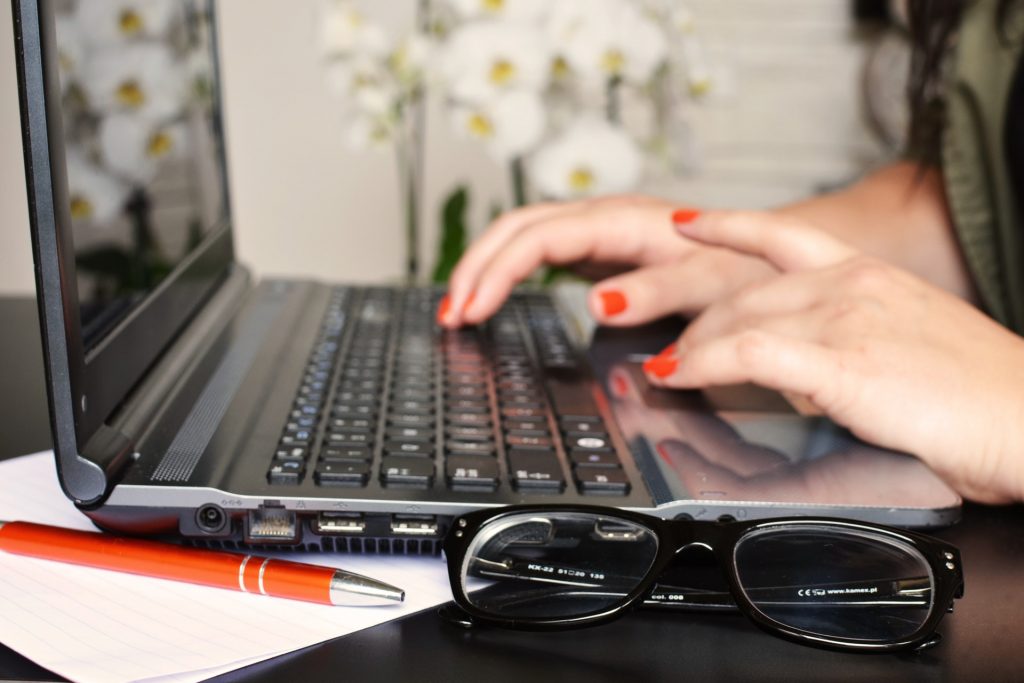 retargeting: mulher digitando em seu computador. Há um óculos de grau à frente. 