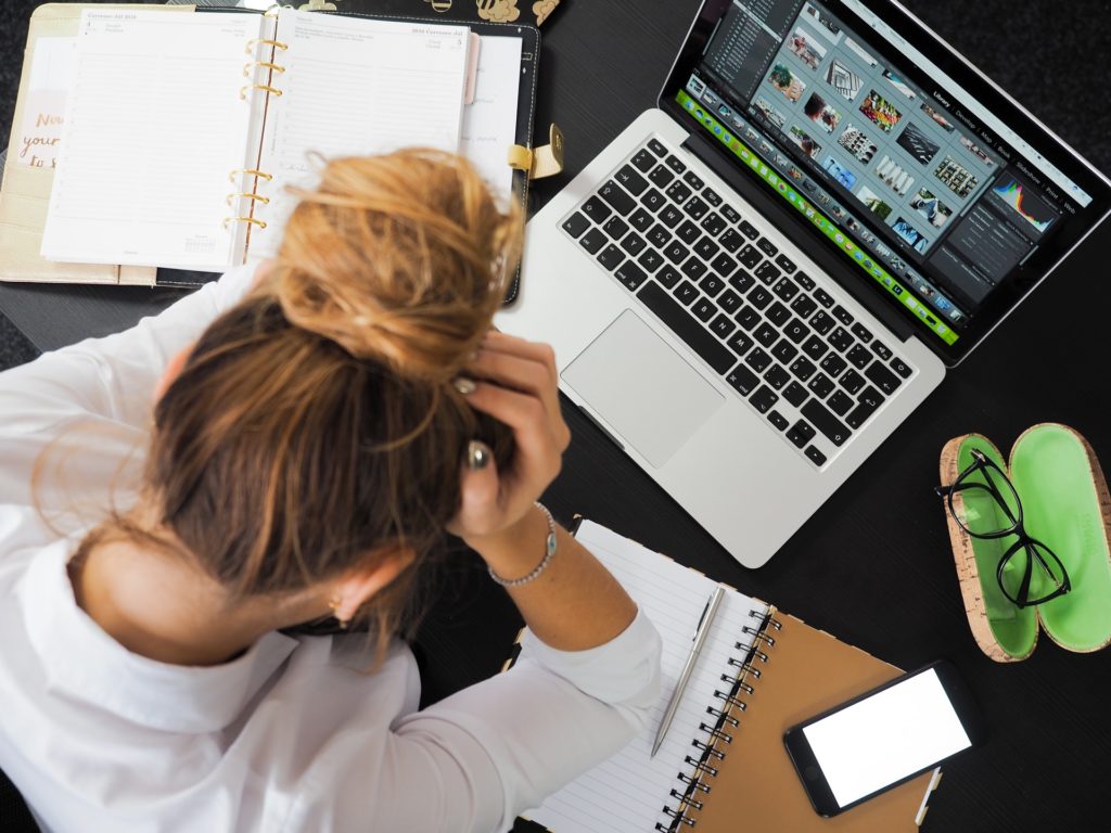 Problemas startup: mulher com as mãos na cabeça, demonstrando desespero, em frente a um computador.