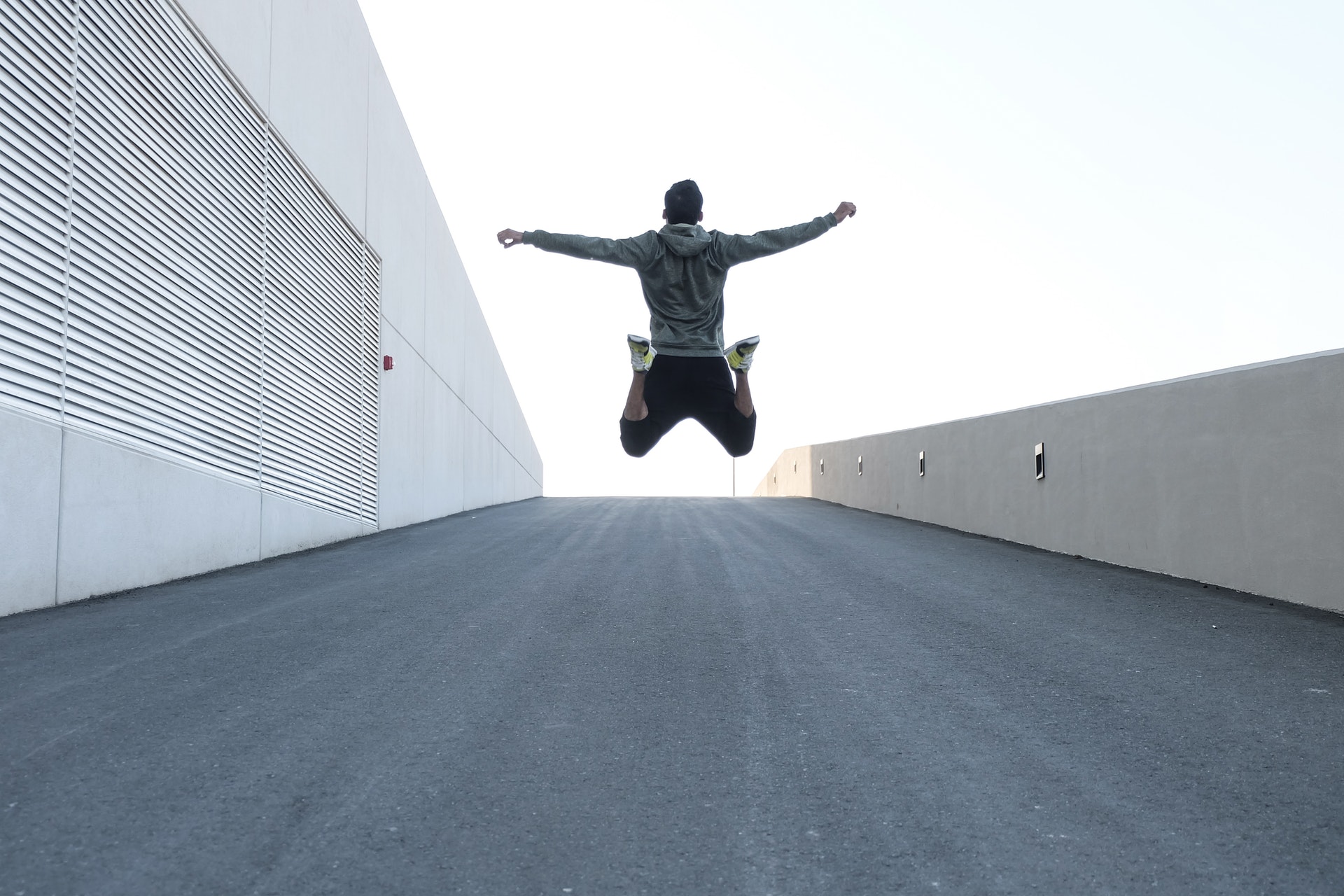 man in gray hoodie jump with open arms 1432580