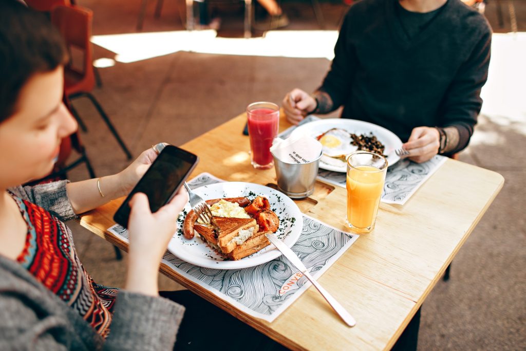 Internet veloz: um casal no restaurante. Os dois olham para seus respectivos celulares.