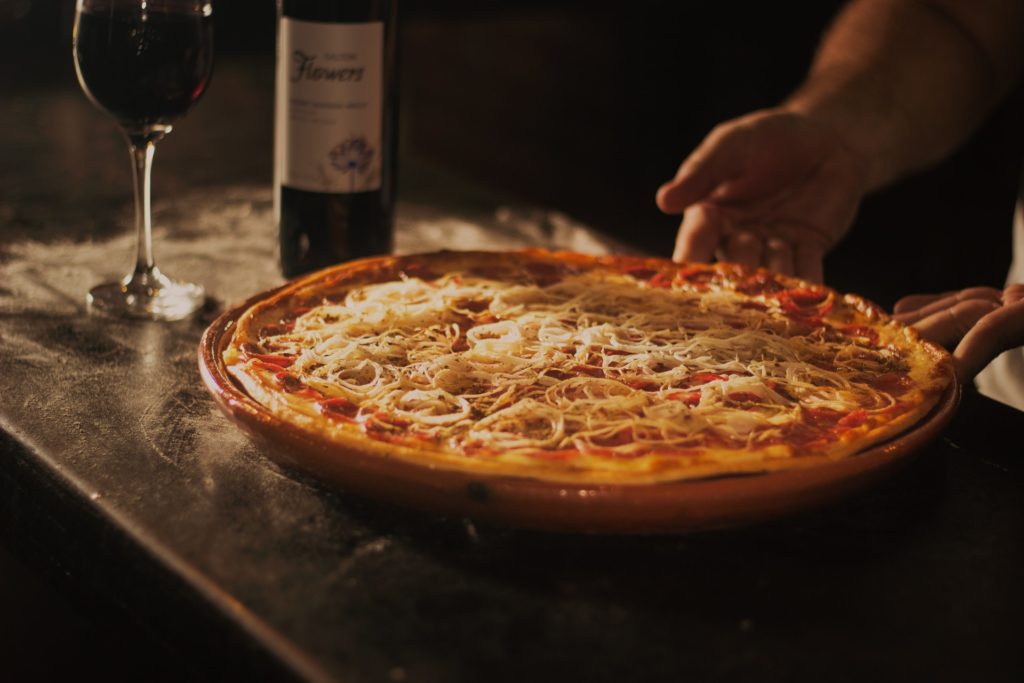 Velocidade melhor: pizza sobre a mesa de madeira, com uma garrafa de vinho ao lado.