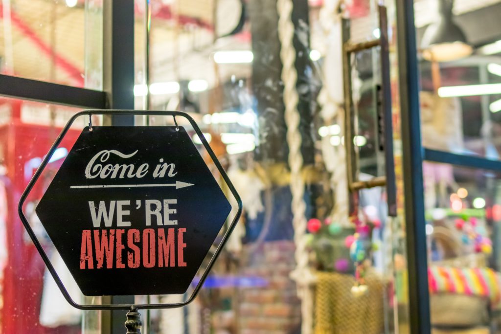 Preço em tempo real: placa com o texto "Come in. We're awesome" em frente a uma loja