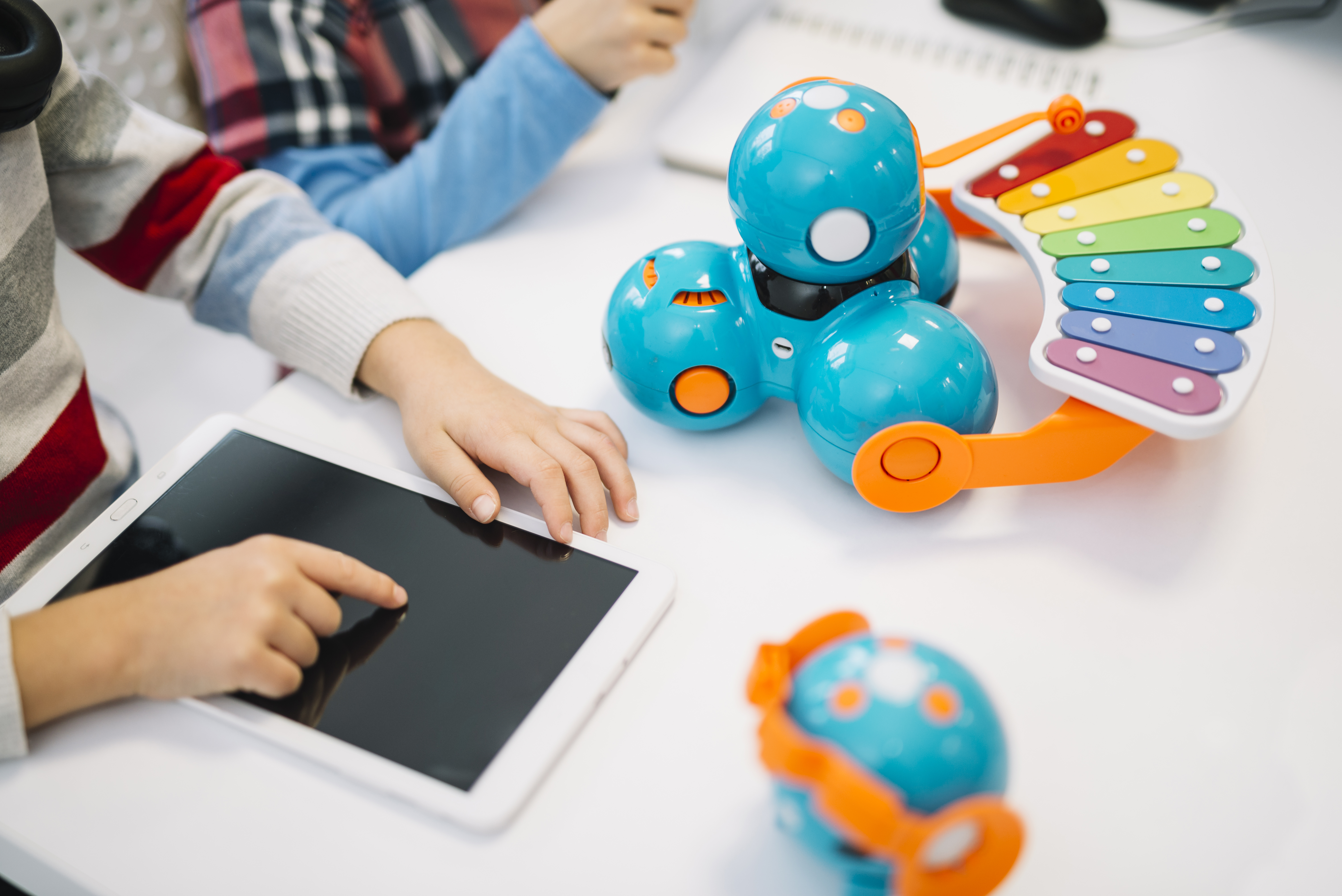 aulas à distância: imagem de uma criança tocando um tablet ao lado e um brinquedo. 