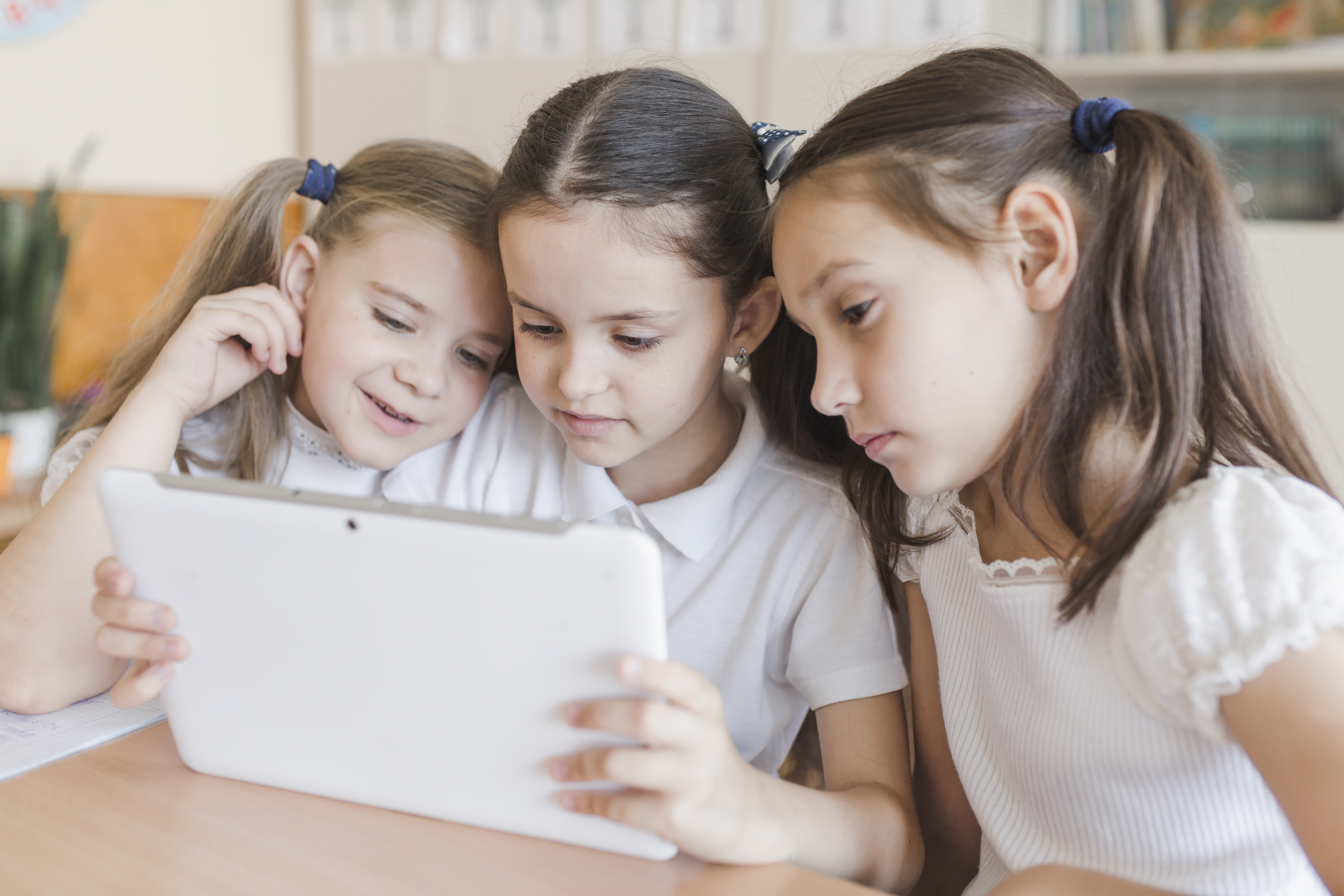 aulas à distância: 3 crianças lendo um mesmo tablet. 