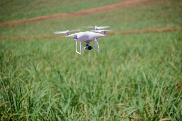 Imagem de um drone sobrevoando um campo rural. 