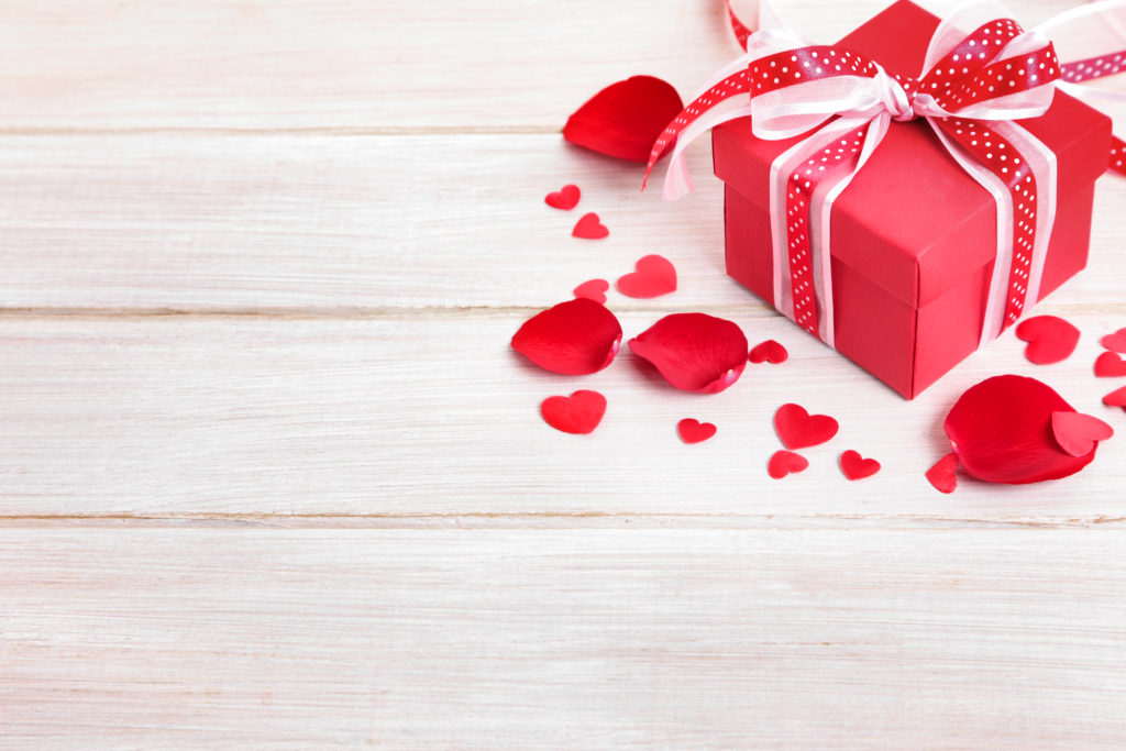 Imagem de uma caixa de presente vermelha em cima de uma mesa para simbolizar o dia dos namorados. 