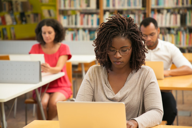 Imagem de alunos sentado em salas de aula com um computador na mesa para simbolizar vestibulares online. 