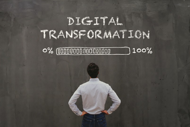 Imagem de um homem olhando para a parede onde está escrito transformação digital. 