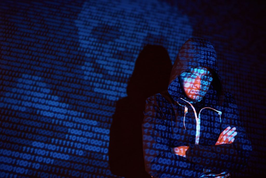 Homem de touca com códigos e scripts ilustrando o ataque a dados das empresas