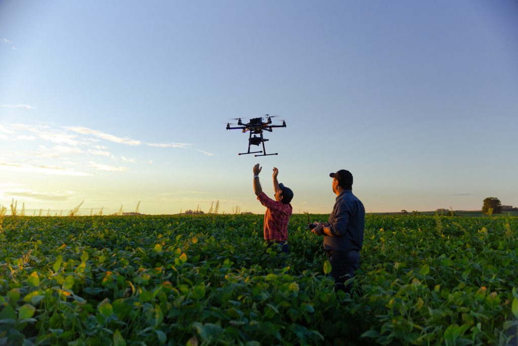 Dois fazendeiros operando drone em plantação