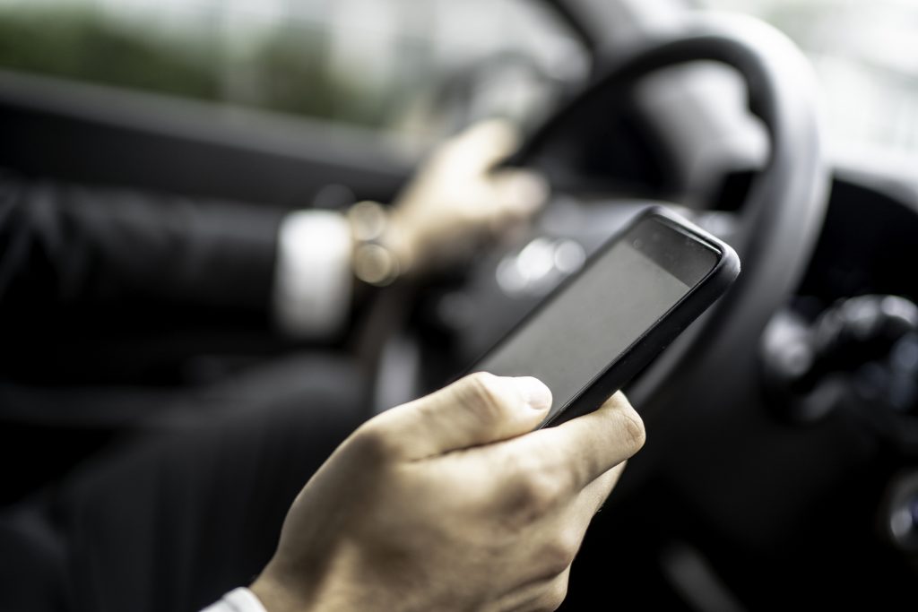 Close de motorista de aplicativo usando o celular no carro, representando a economia compartilhada