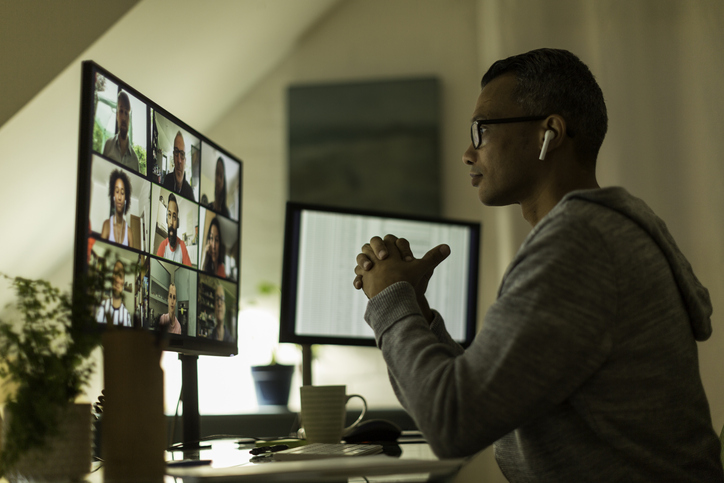 Pessoa trabalhando em casa olhando para monitores enquanto faz reunião online
